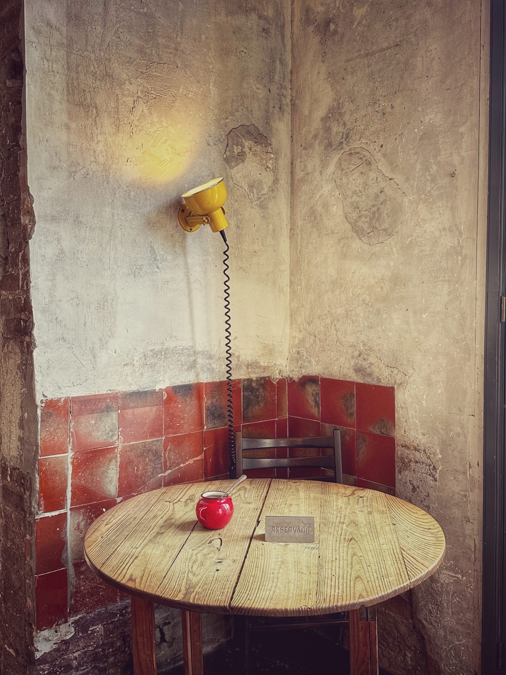 A table with a lamp in a small room.