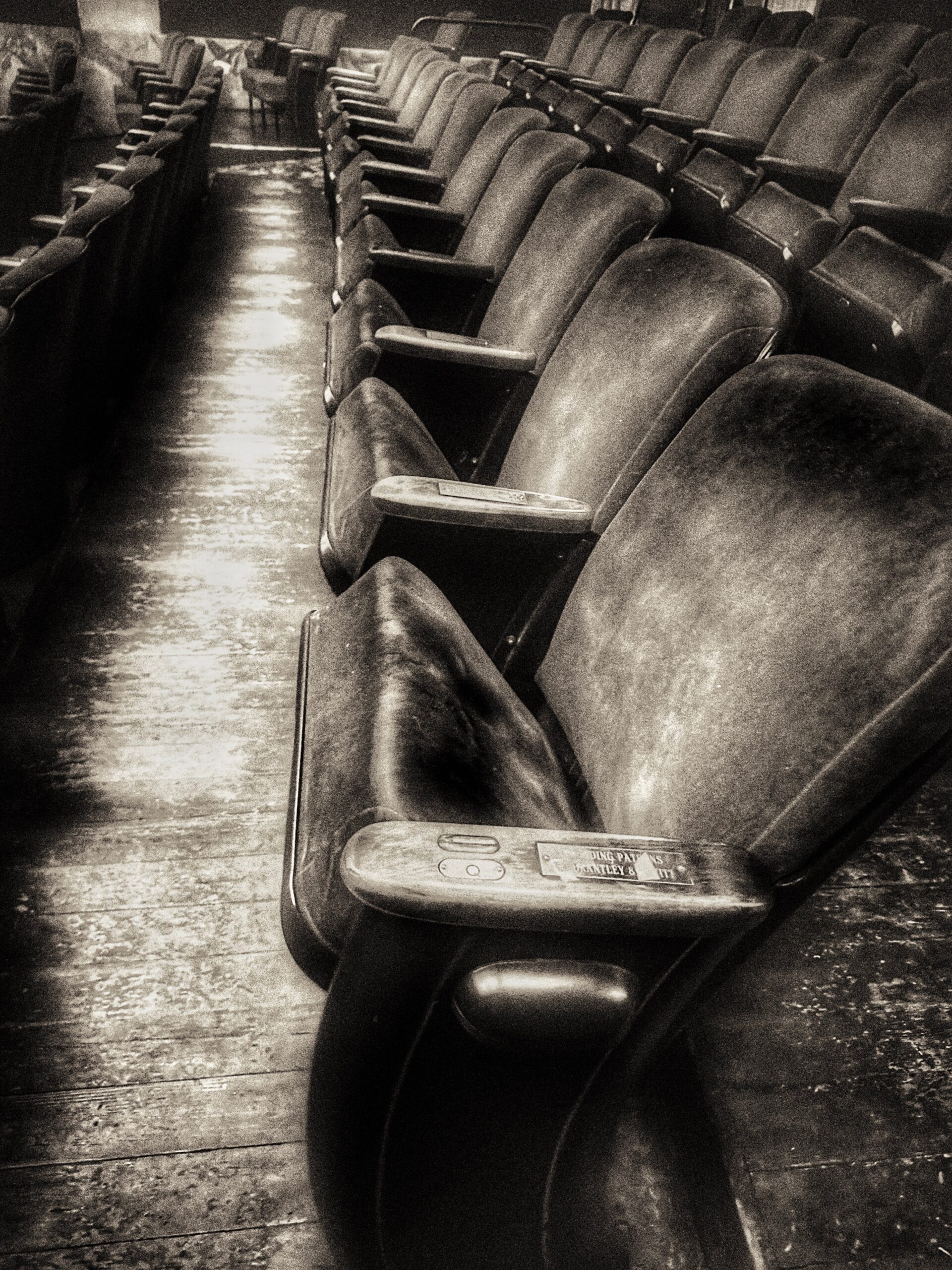 Black and white photograph of rows of empty seats in an auditorium.