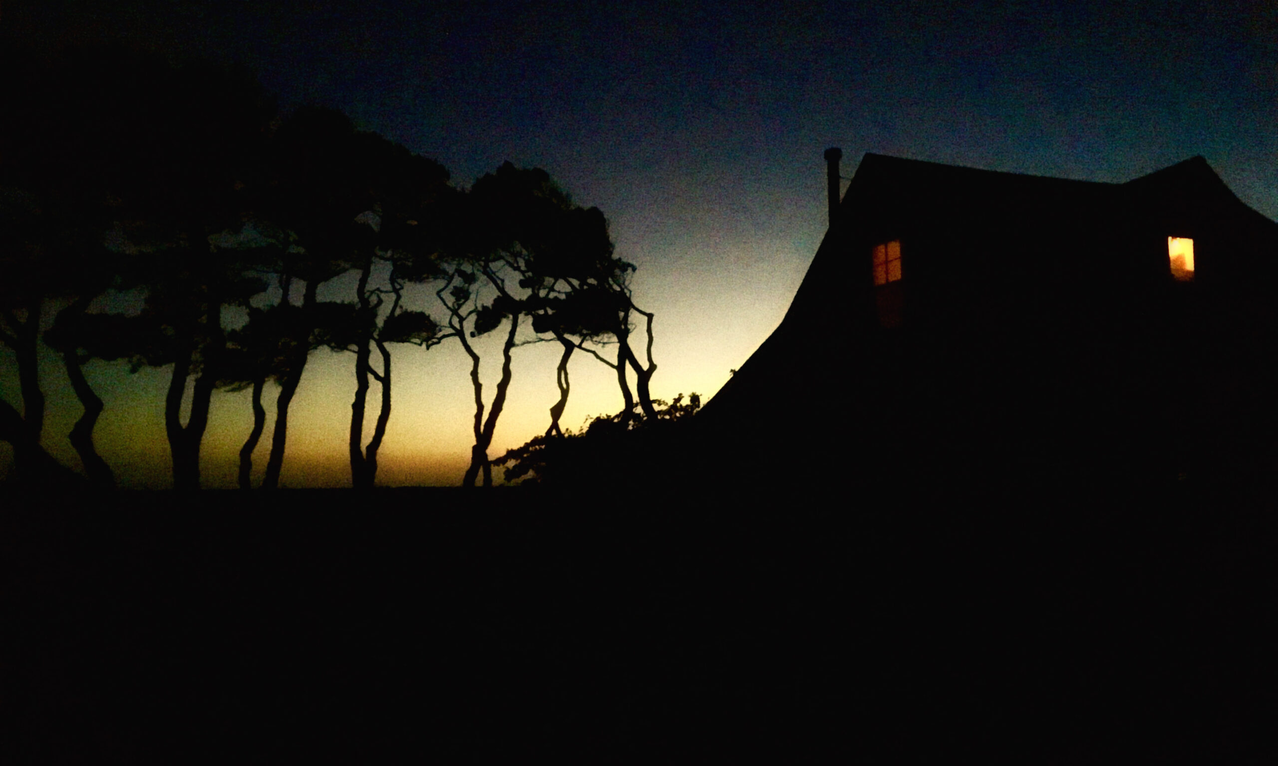 A silhouette of a house at dusk.