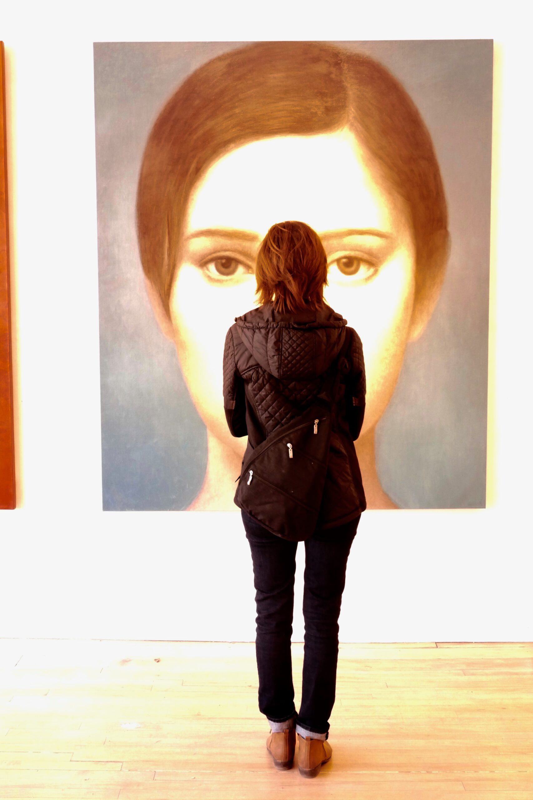 A woman standing in front of a painting.