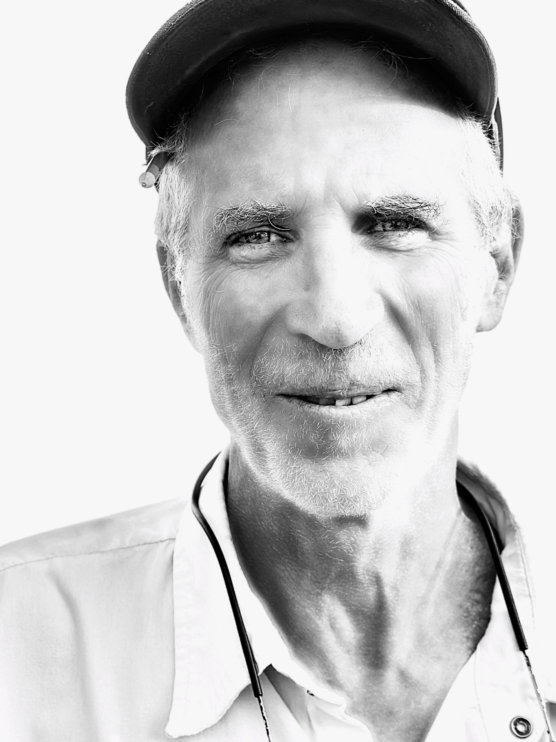 A black and white photo of an older man wearing a baseball cap.