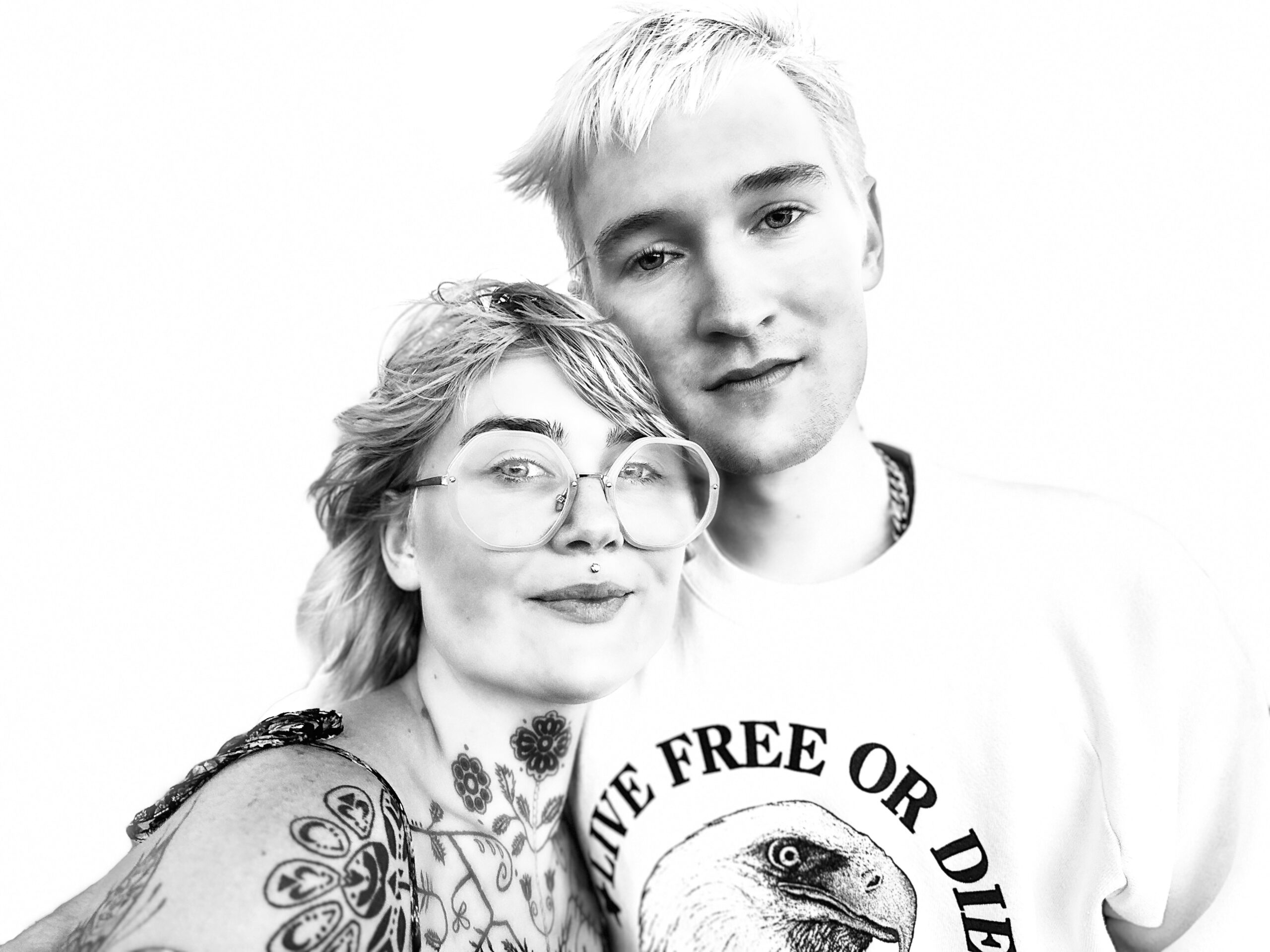 A black and white photo of two people  with tattoos.