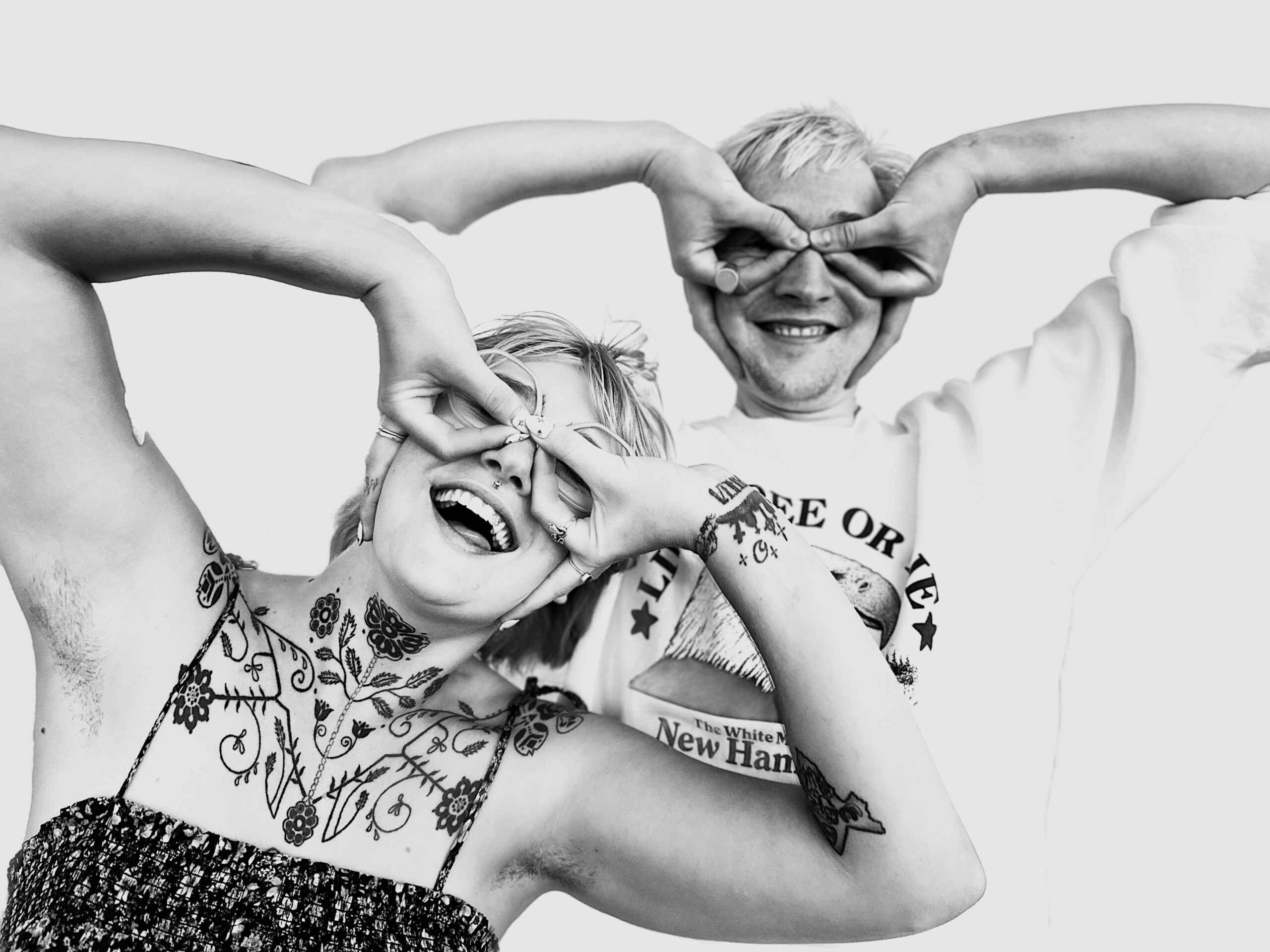 A black and white photo of two people making faces with their hands.