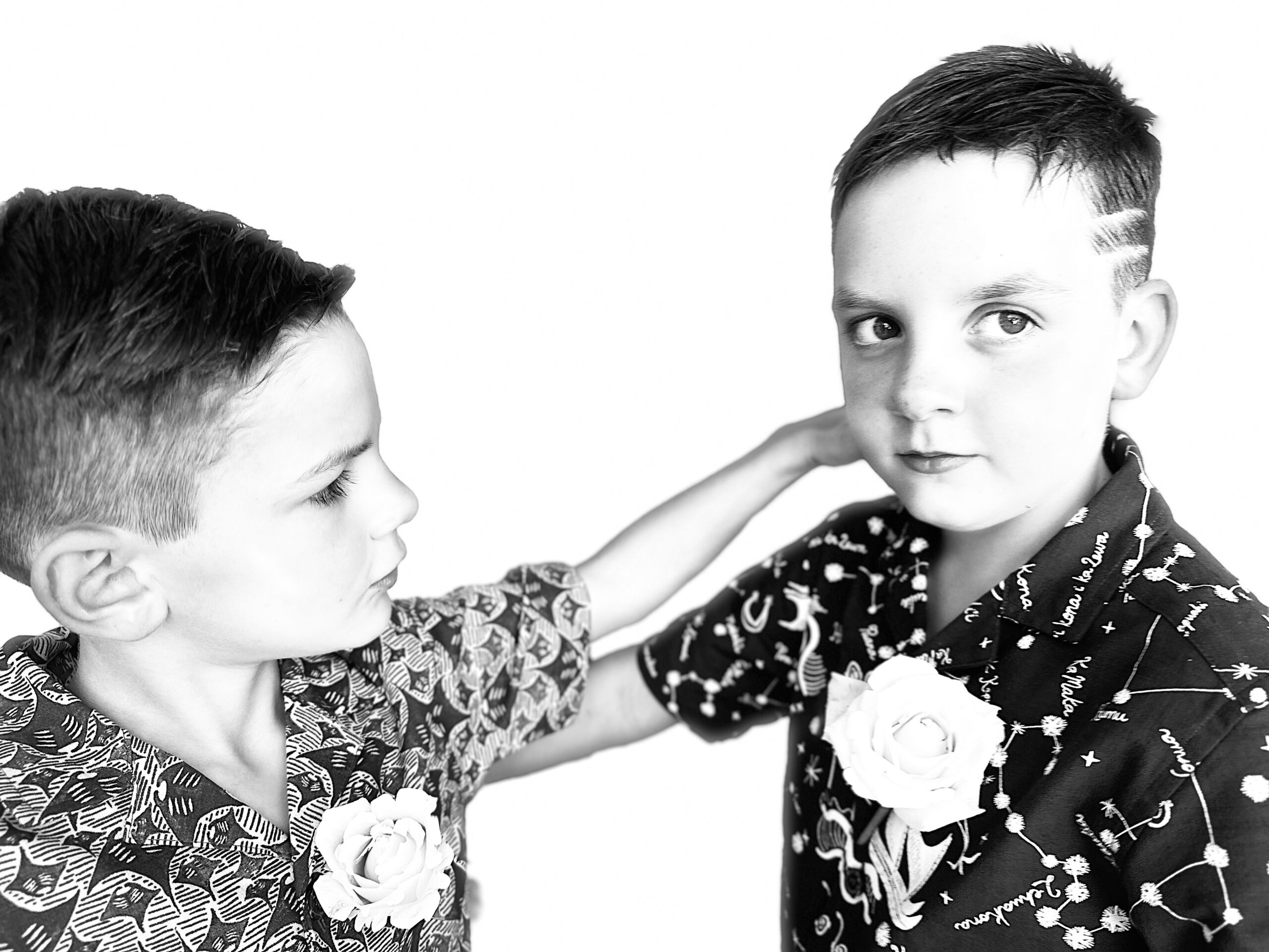 Two boys are pointing at each other in a black and white photo.