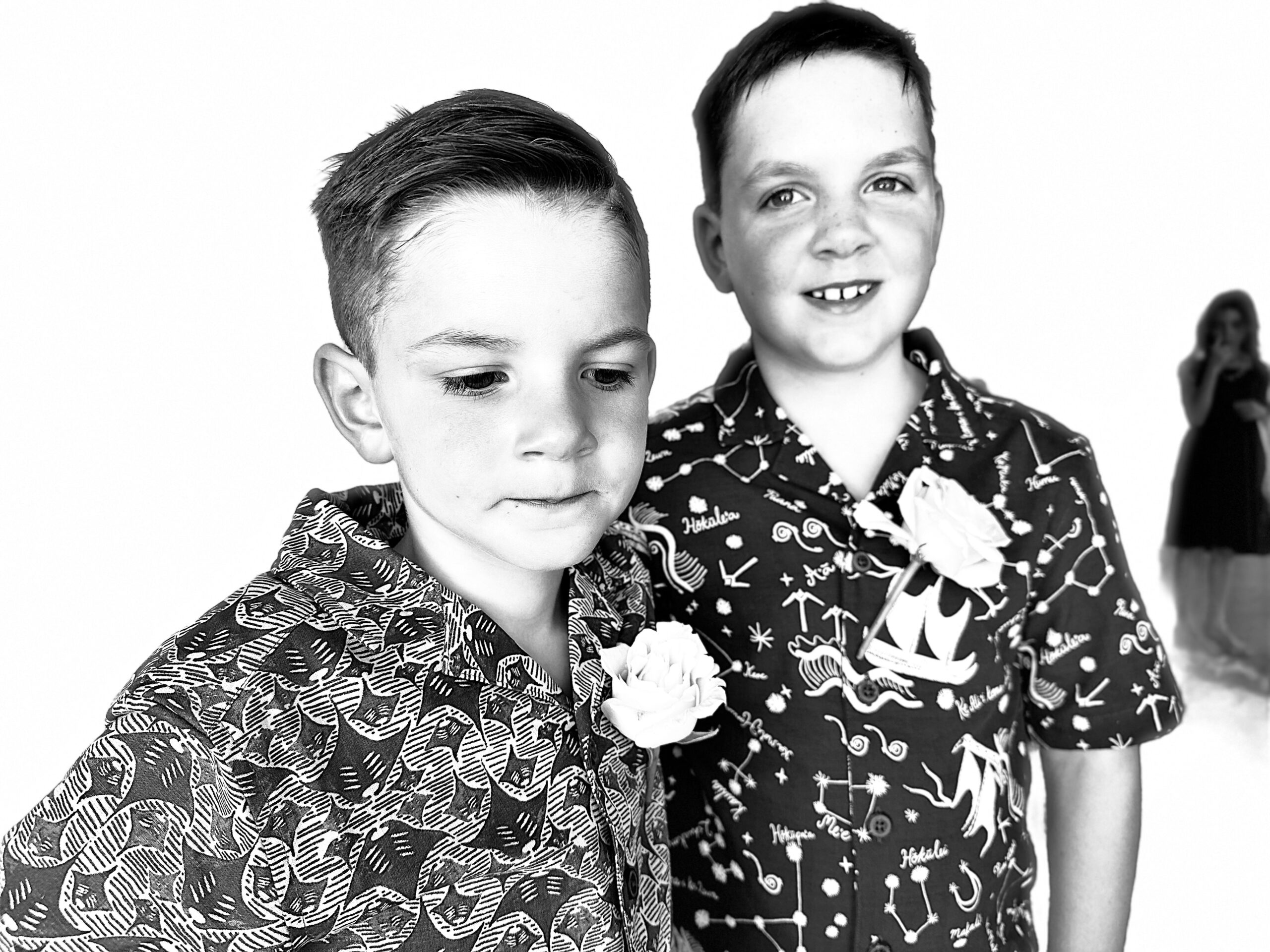 Two boys in hawaiian shirts posing for a photo.