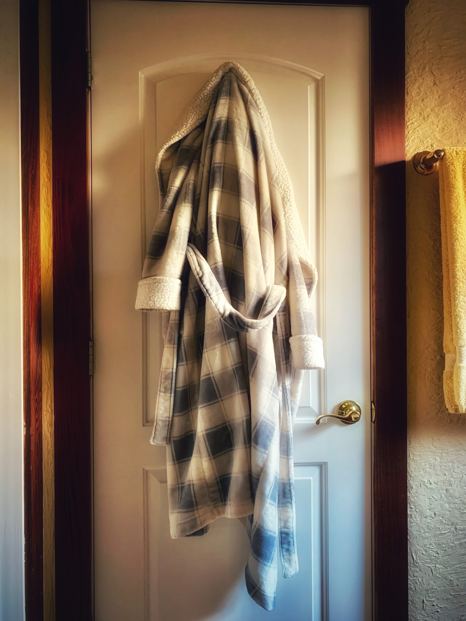 A robe hanging on the door of a bathroom.