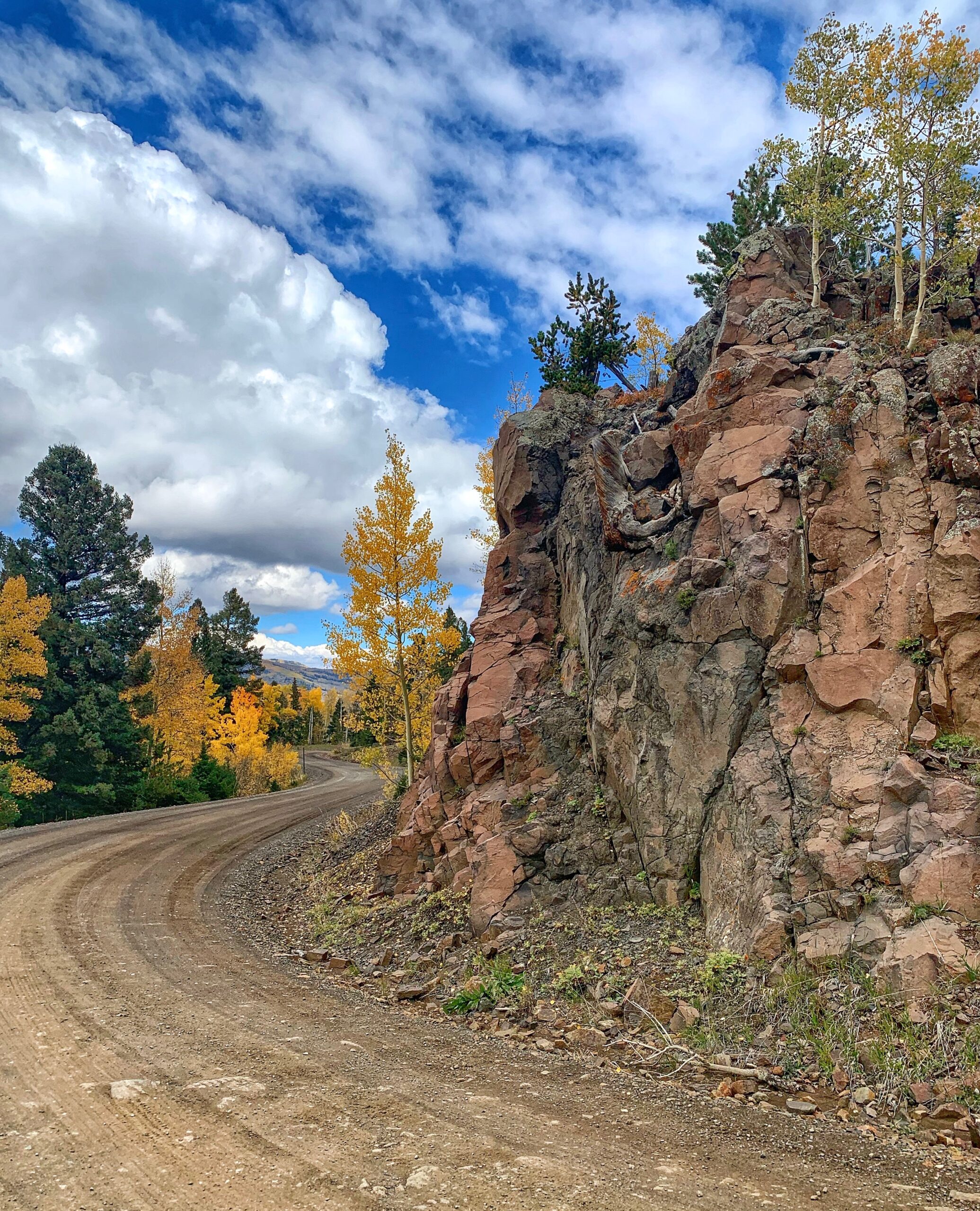 A dirt road next to a rocky cliff.