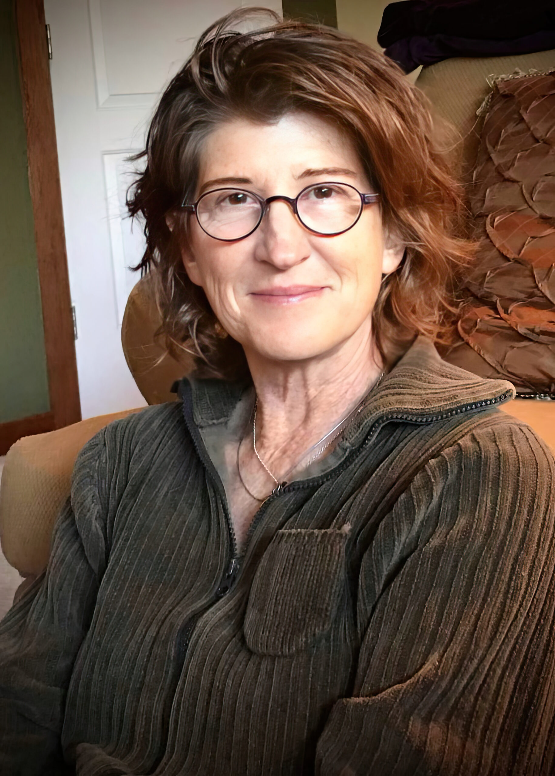 A woman in glasses sitting on a couch.